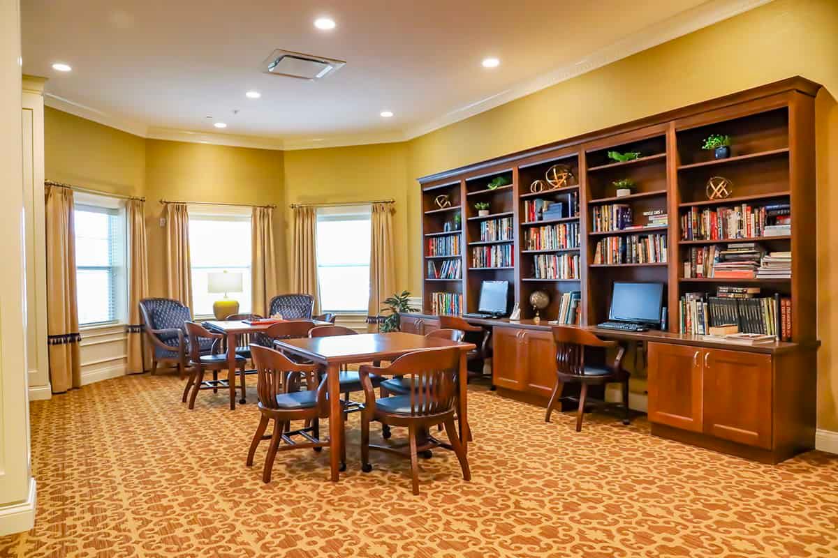 A well-lit library room with bookshelves, computers, tables, and chairs for reading and studying.