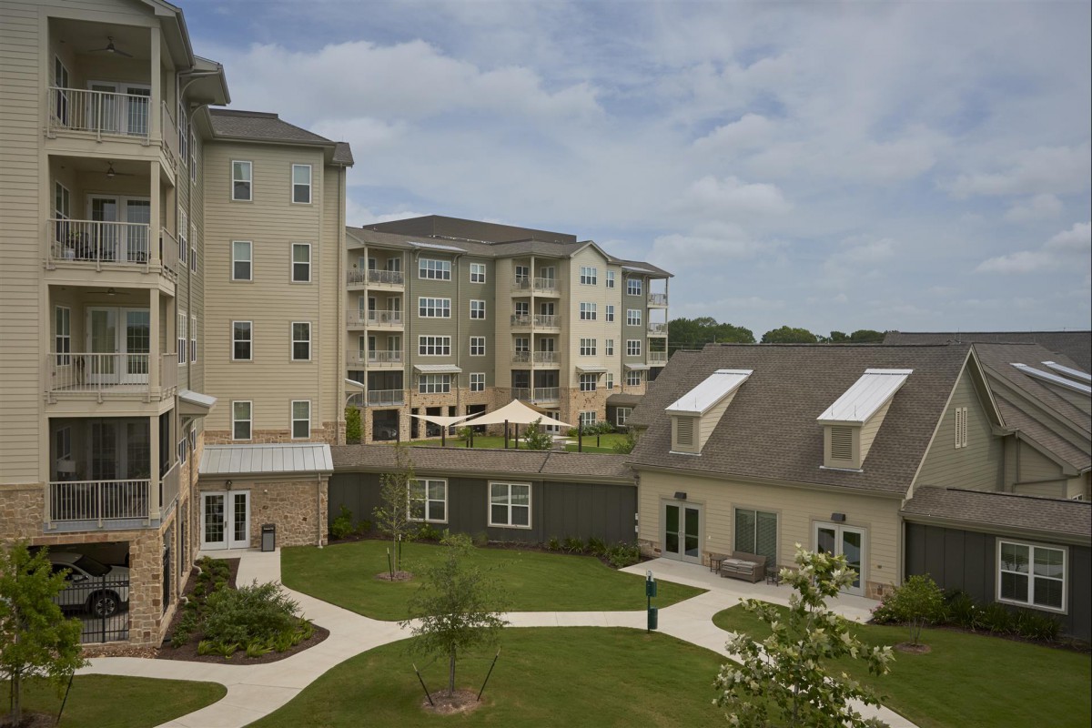 A view of a residential apartment complex with well-maintained gardens and pathways.
