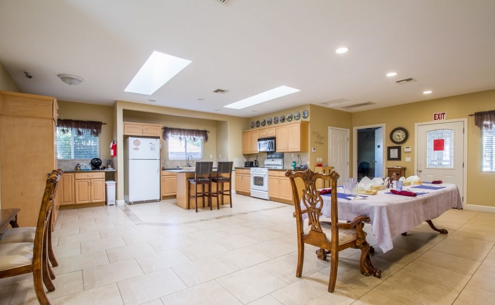 A spacious modern kitchen with wooden cabinets and a dining area, featuring skylights and tiled flooring.