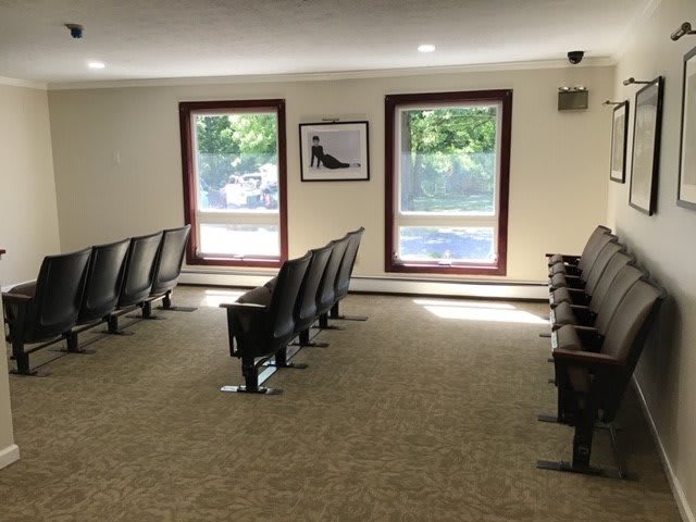 A quiet waiting room with rows of chairs and large windows providing natural light.