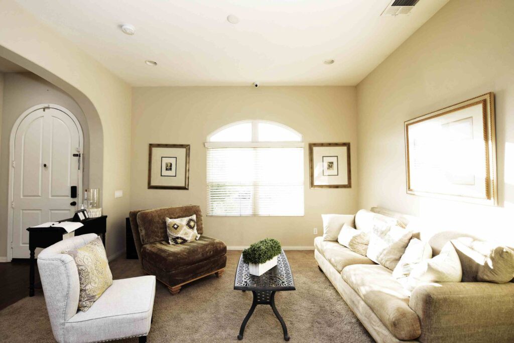 A cozy living room with neutral tones, featuring a sofa, an armchair, and a coffee table.