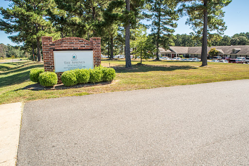 An inviting entrance featuring a sign surrounded by greenery and trees.