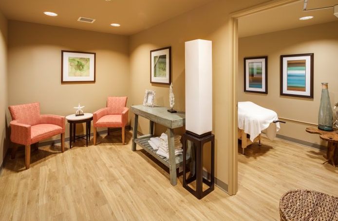 A calming spa environment featuring a massage room with soft lighting and comfortable seating area.