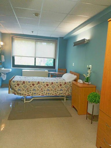 A well-organized hospital patient room featuring a bed, functional furniture, and a calming blue color scheme.