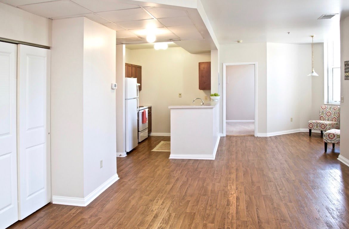 A modern apartment interior with an open kitchen layout and wood flooring.