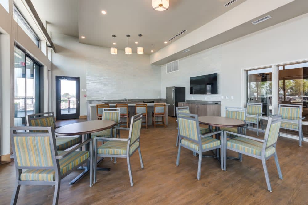A modern dining area with tables and chairs, featuring overhead lighting and hardwood floors.