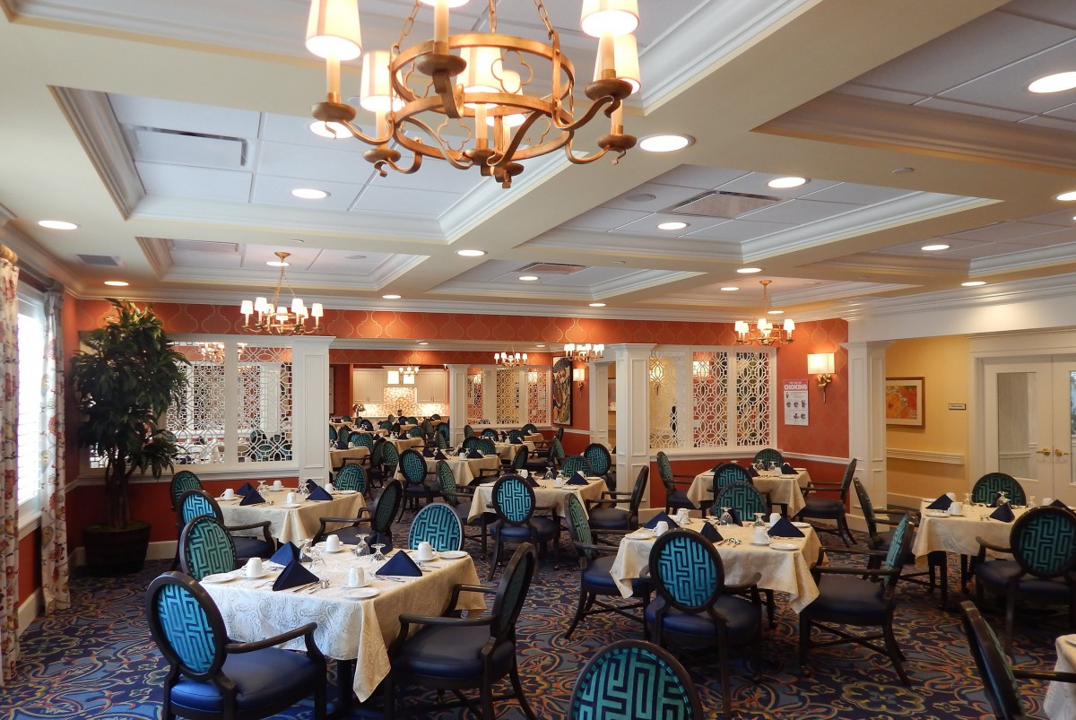 An elegant dining room with neatly arranged tables and chairs, illuminated by stylish chandeliers.
