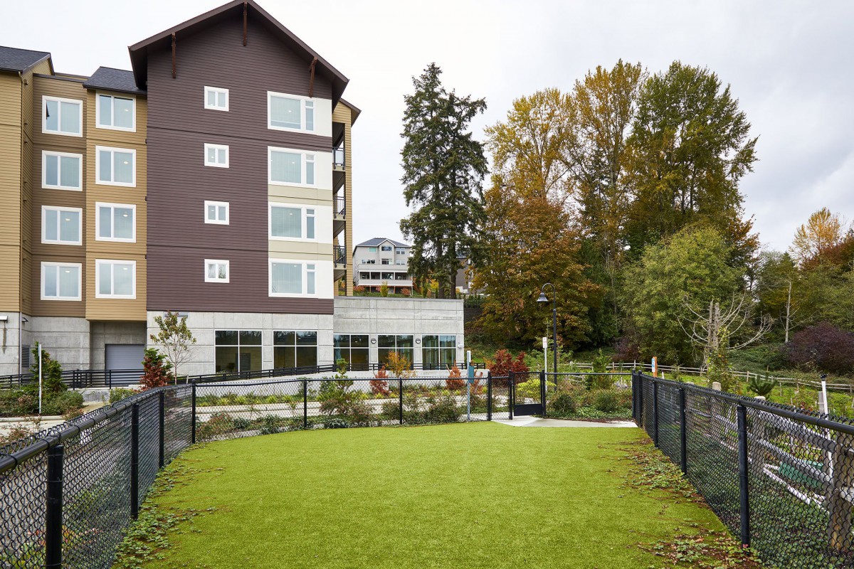 An apartment building with a well-maintained lawn and surrounding trees.