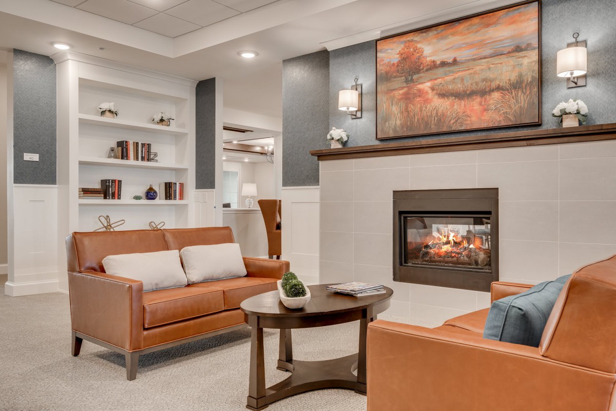 A cozy and beautifully decorated living room with modern furniture, a fireplace, and artwork above the mantel.