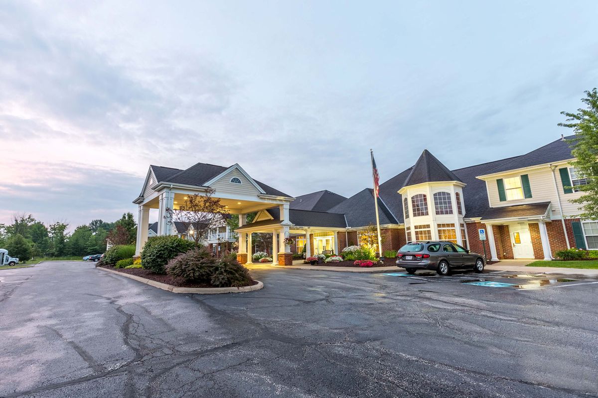 An exterior view of a hotel with a spacious parking lot and illuminated entrance.