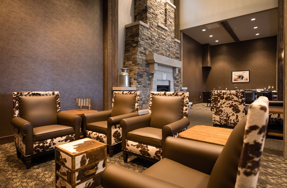 A modern and cozy lounge area with comfortable armchairs and a stone fireplace.