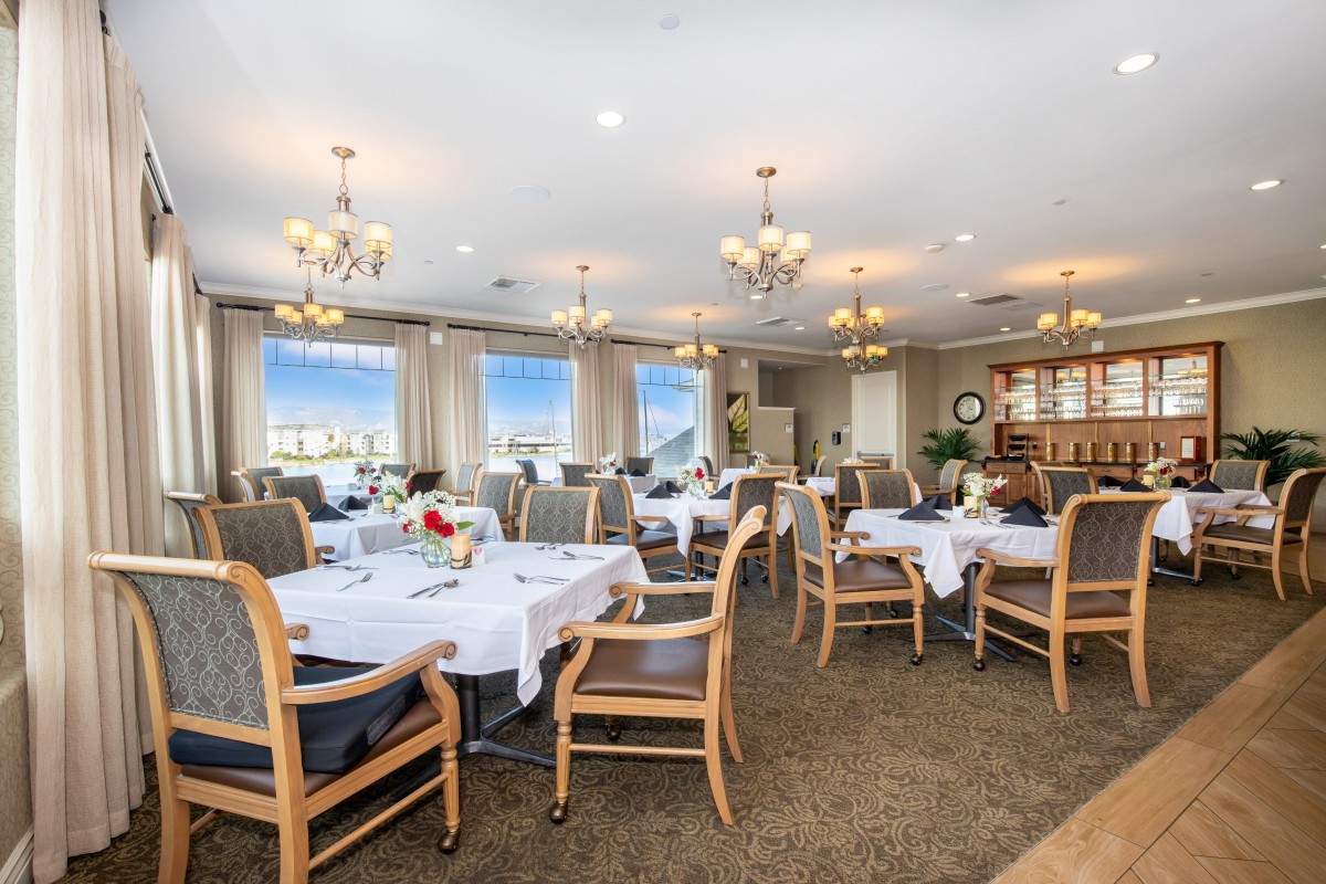 An elegant dining room with neatly arranged tables and chairs, adorned with chandeliers.