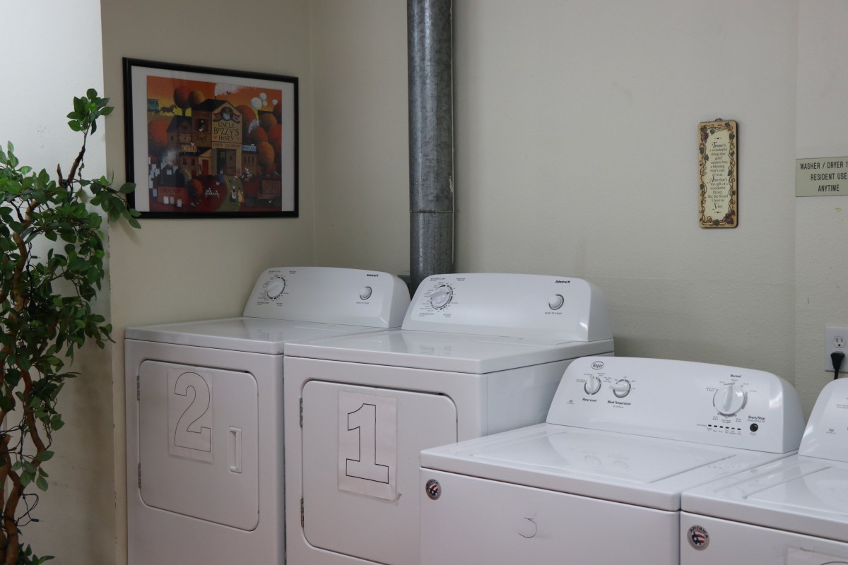 A clean and organized laundry room with washers and dryers.
