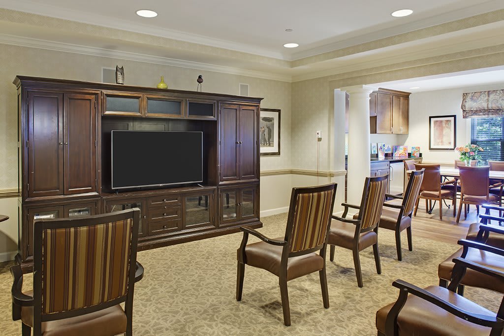 A well-arranged living room with chairs facing a television on a wooden cabinet.