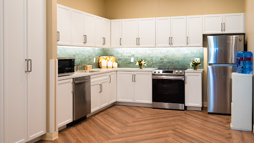 A modern kitchen featuring white cabinets, sleek appliances, and a stylish green backsplash.