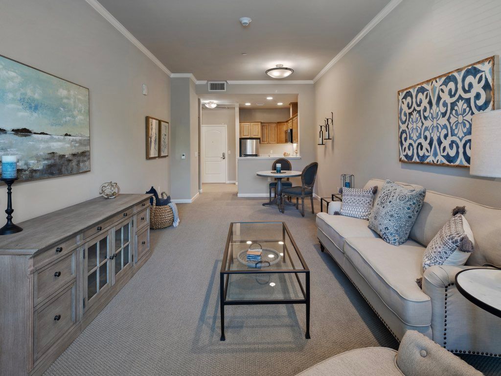 A modern living room with a sofa and a glass coffee table, featuring contemporary decor.