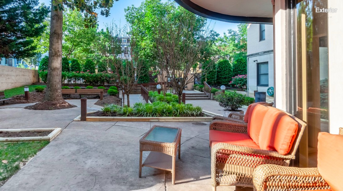 A serene outdoor patio area featuring comfortable seating and lush garden surroundings.