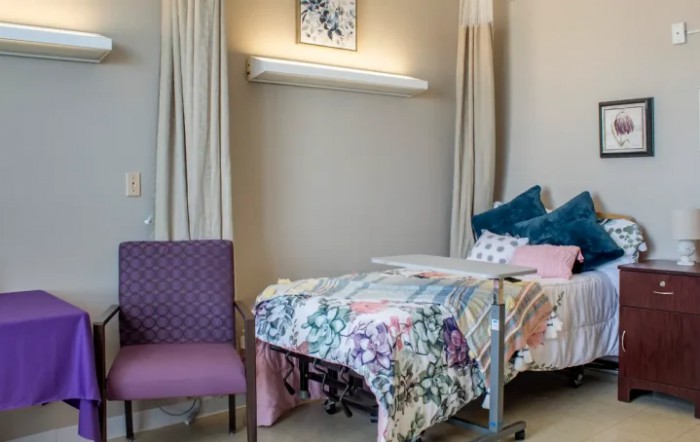 A well-decorated hospital room with a bed and chair.