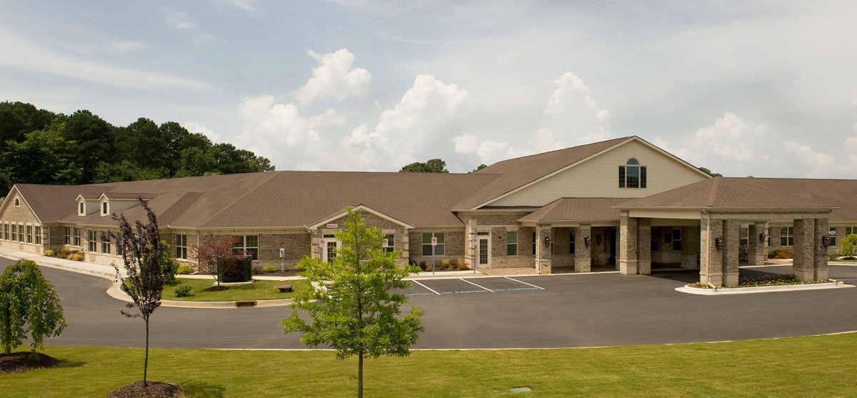 A suburban building with a stone facade and a manicured lawn under a cloudy sky.