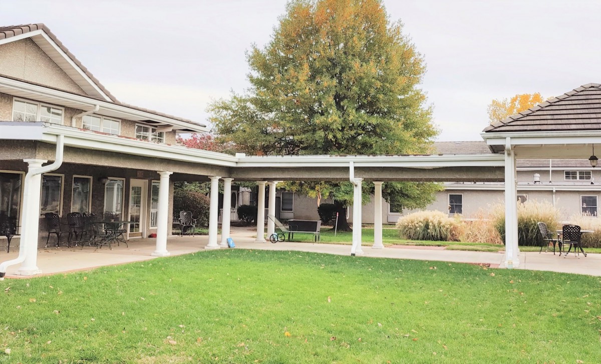 A scenic view of a courtyard with a covered walkway and lush green lawn.