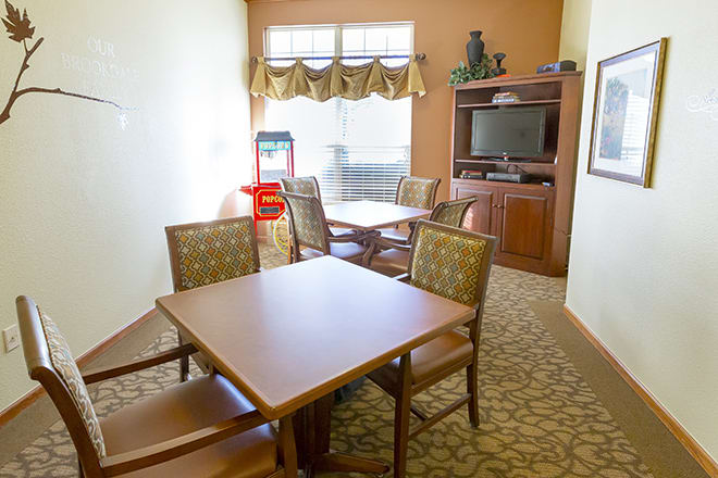 A cozy dining area with tables and chairs, a television on a cabinet, and a window providing natural light.