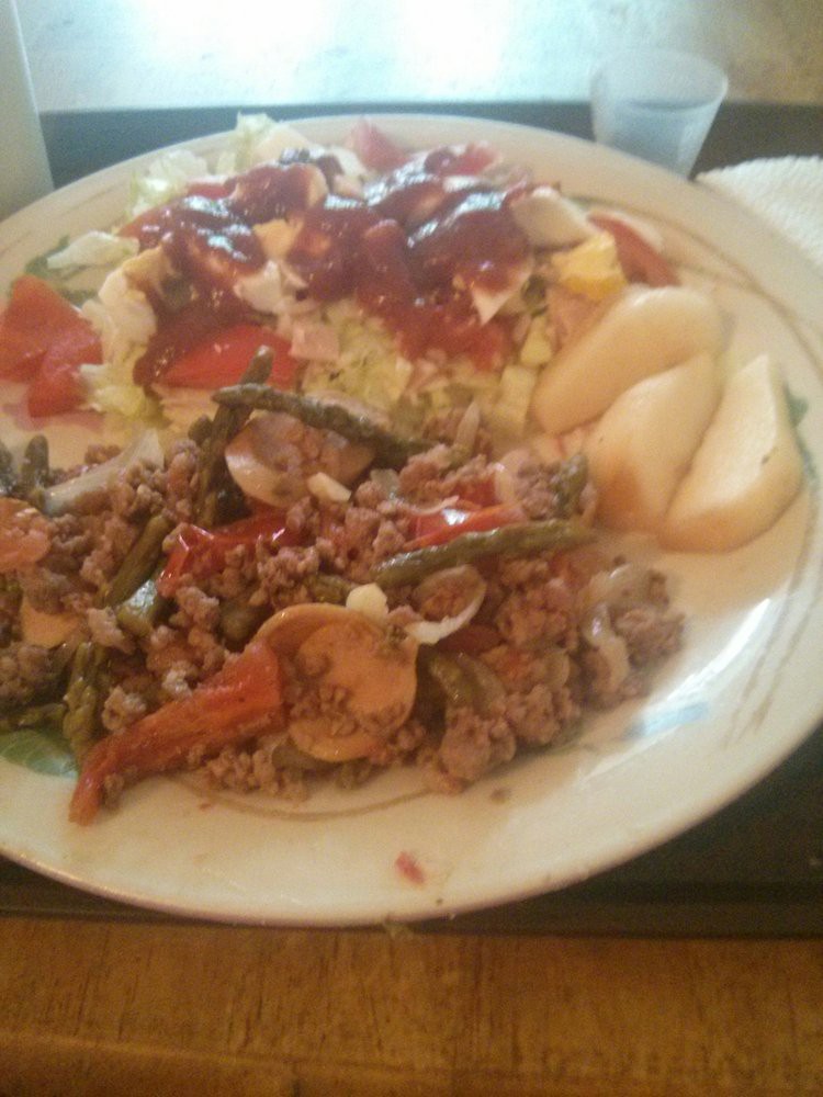A plate with a serving of beef and vegetables, salad topped with dressing, and sliced pears.