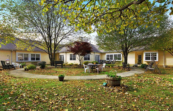 A peaceful garden setting with chairs and a pathway surrounded by autumn foliage.