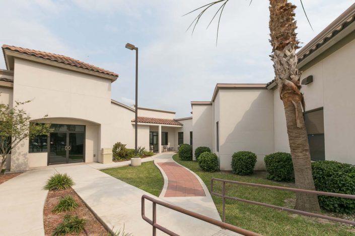 A modern building exterior with a landscaped pathway and greenery.
