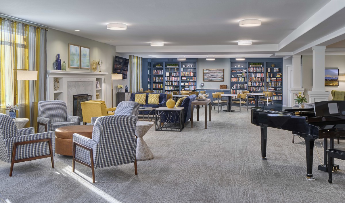 A modern lounge with comfortable seating, bookshelves, and bright lighting.