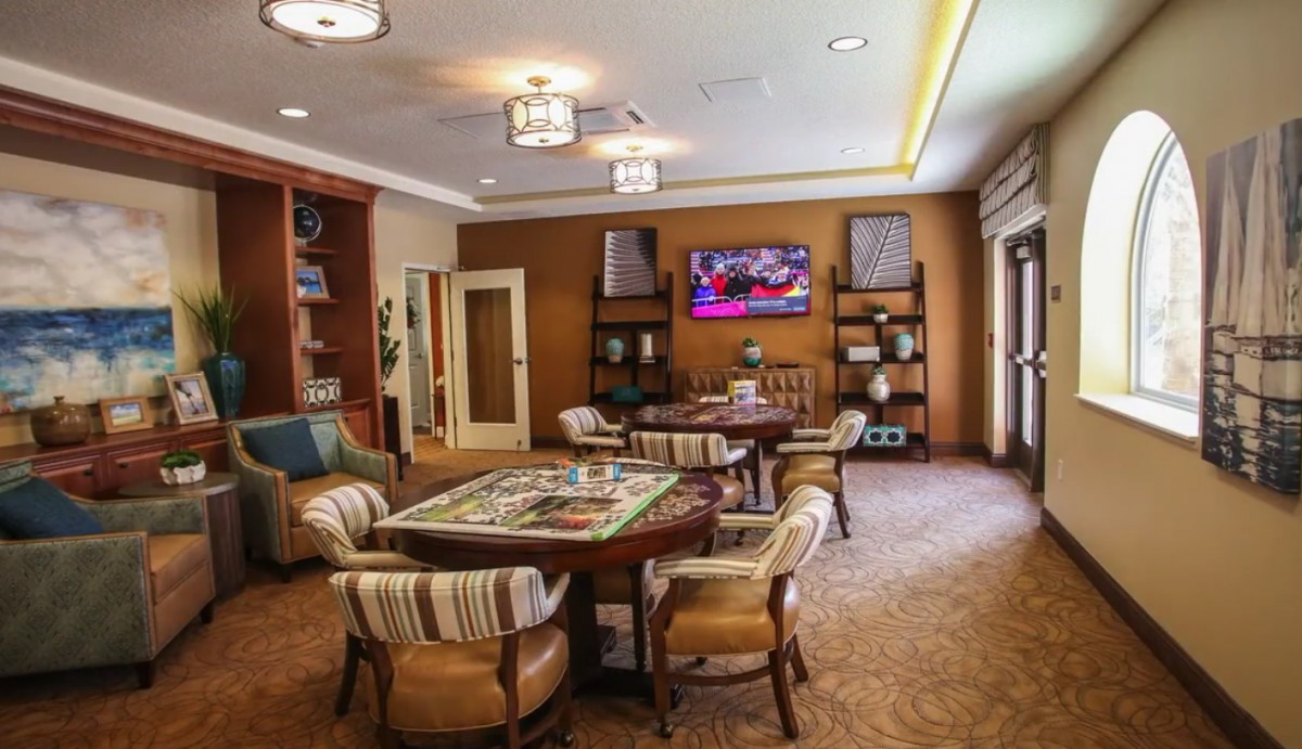 A cozy living room with a table and chairs, TV, and bookshelves.