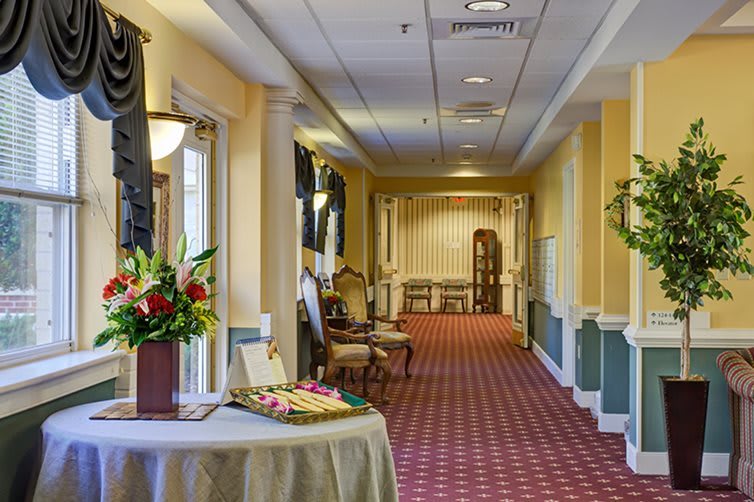 A warmly decorated hallway with vintage furniture and floral arrangements.