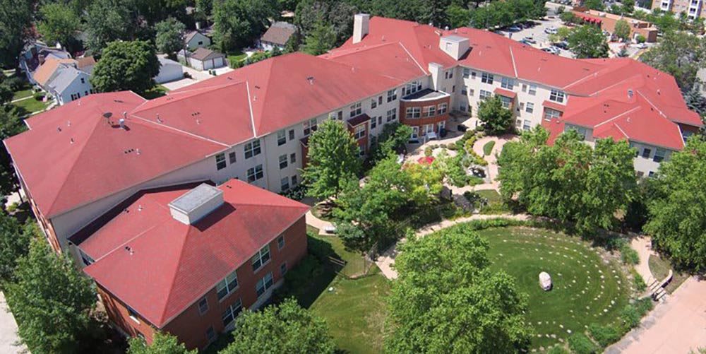 Aerial view of a red-roofed building surrounded by trees and gardens.