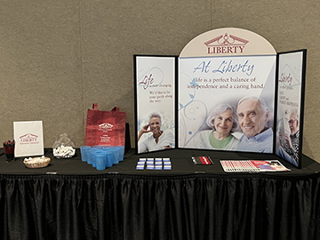 A promotional booth for a senior living community featuring informational materials and branding.