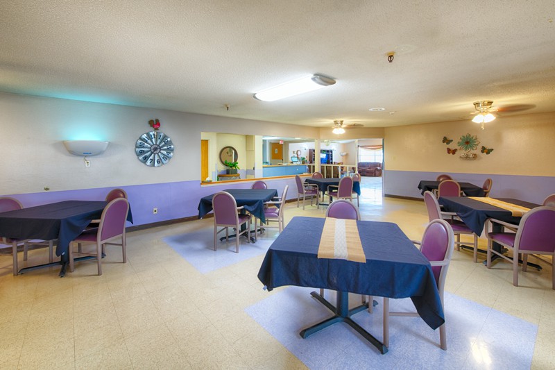An indoor dining area with arranged tables and chairs, featuring decorative elements on the walls.