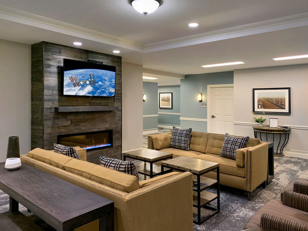 A cozy and modern living room with comfortable sofas, a television mounted above a fireplace, and stylish coffee tables.