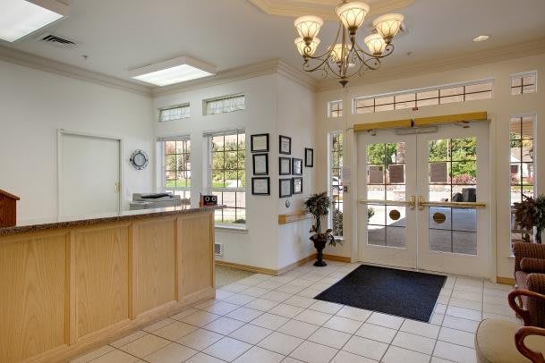 A bright and welcoming lobby area with a reception desk, chandelier, and large windows.