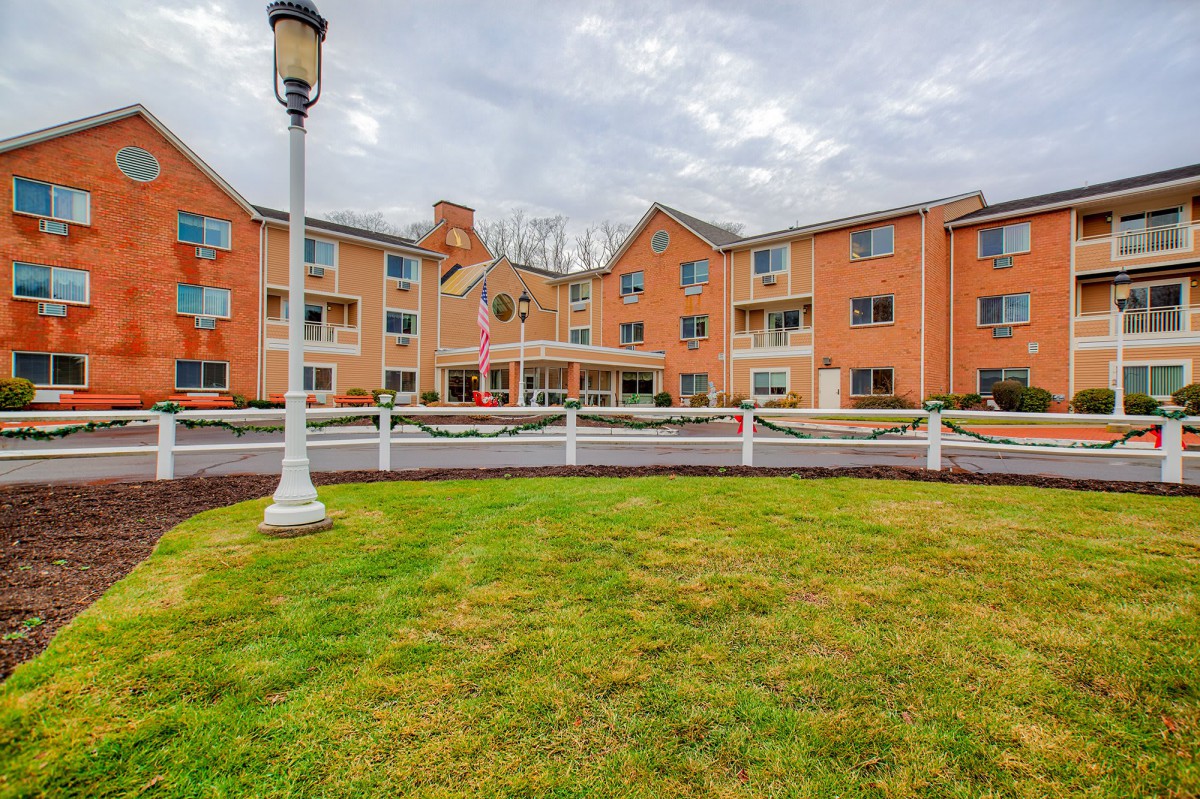 A multi-story residential building with a well-maintained lawn and a lamppost in the foreground.