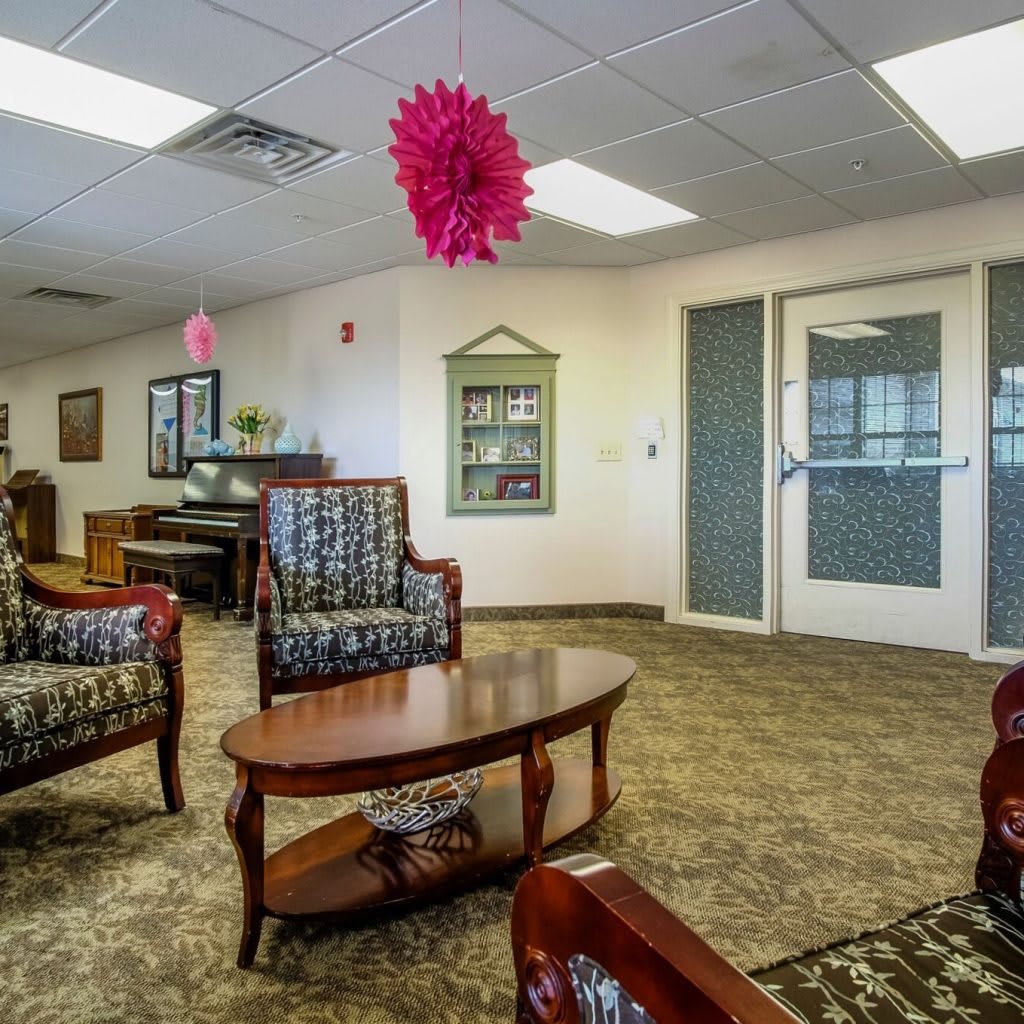 A cozy lobby with upholstered chairs, wooden tables, and ceiling decorations.