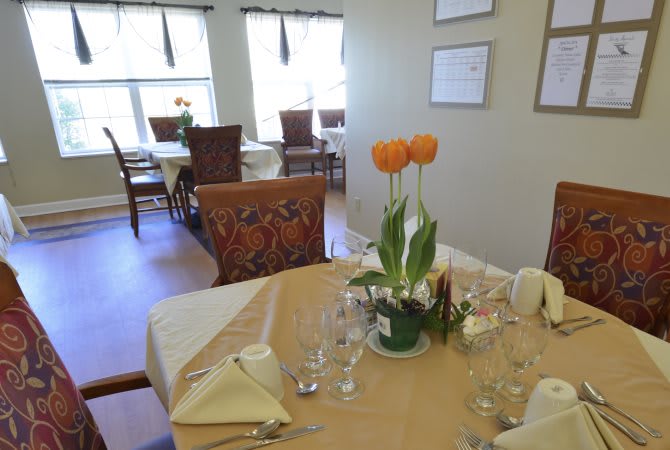 A tastefully set dining table with orange tulips in a cozy restaurant.