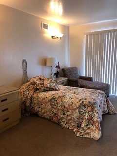 A cozy bedroom with floral bedding and a comfortable chair.