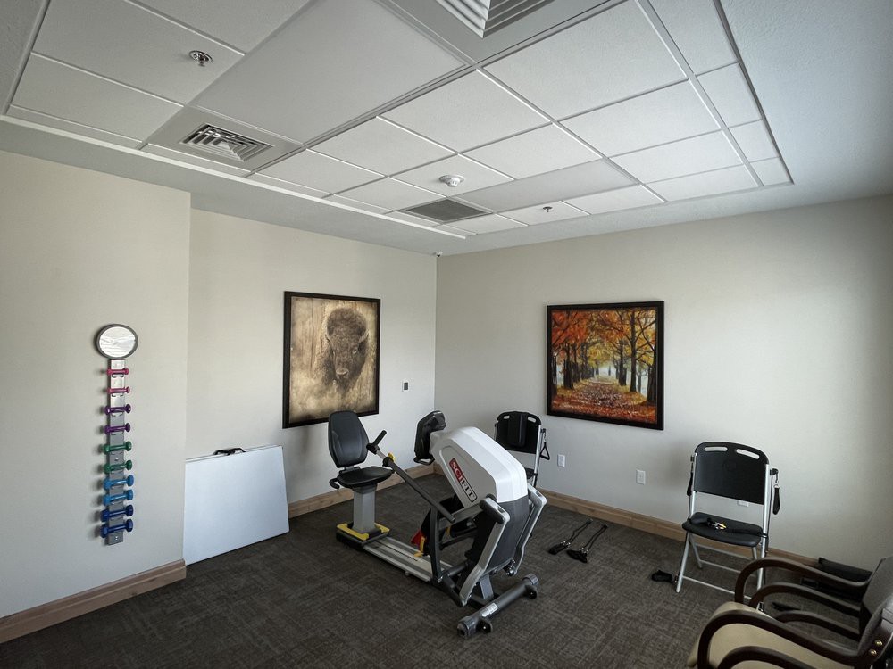 A small exercise room with fitness equipment and decorative artwork on the walls.