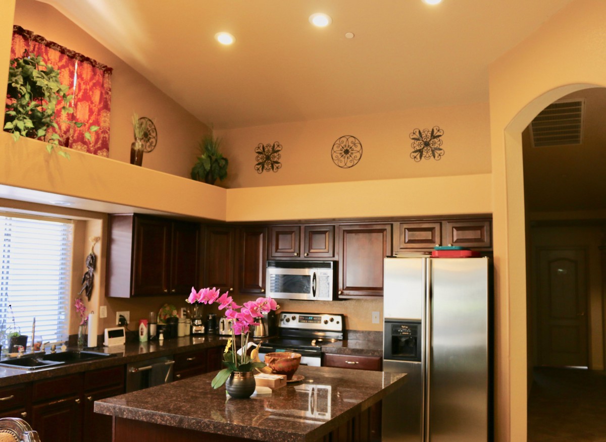 A modern kitchen interior with stainless steel appliances, decorative elements, and a flower arrangement on the countertop.