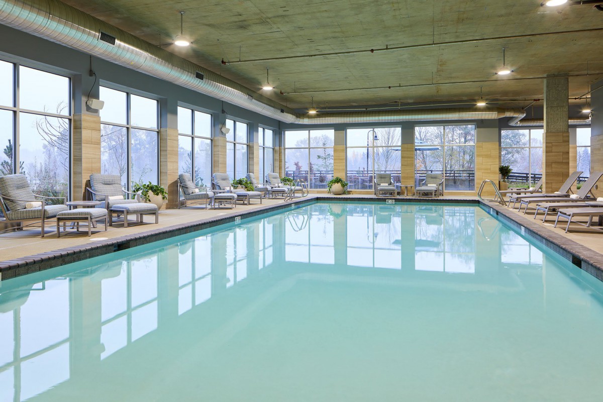 A serene indoor swimming pool area with lounge chairs and large windows providing natural light.