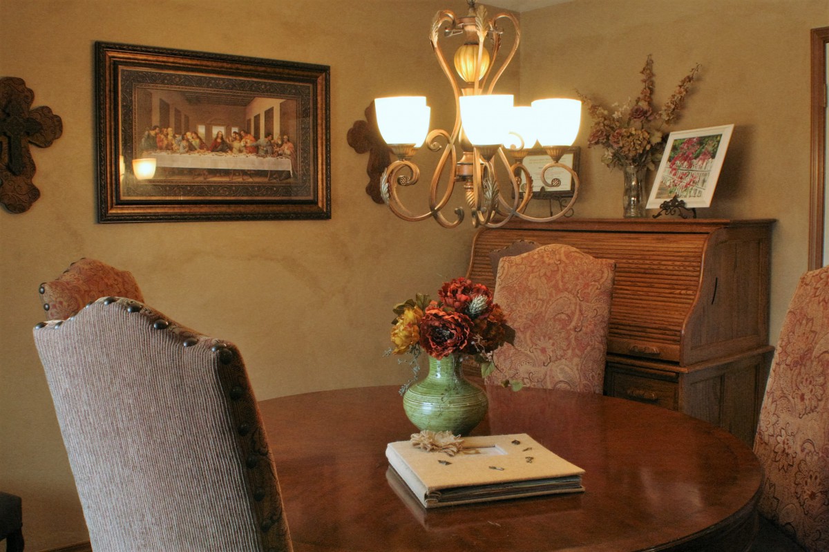 A cozy dining room featuring a chandelier, a wooden table with a vase of flowers, and elegant decor.