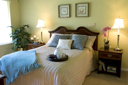 A cozy bedroom with a neatly made bed, decorative pillows, and warm lighting.
