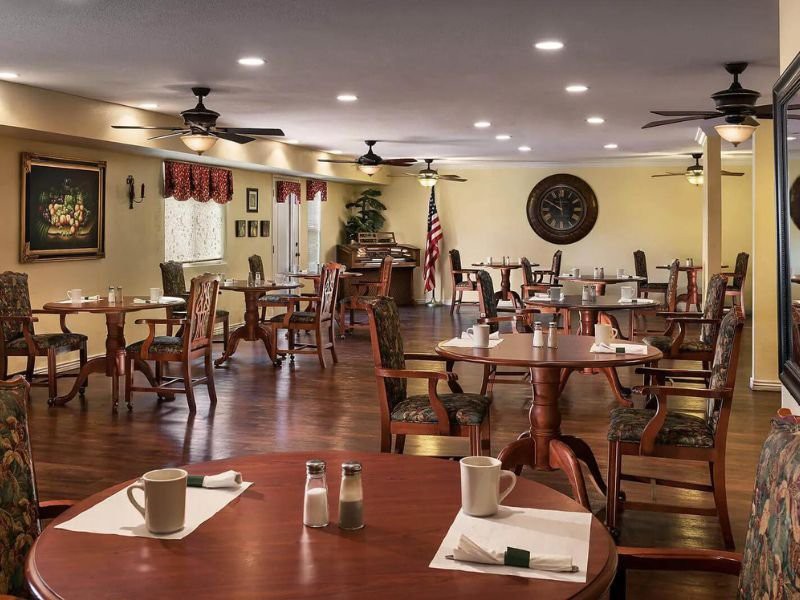 An empty dining room with neatly arranged tables and chairs, ready for guests.