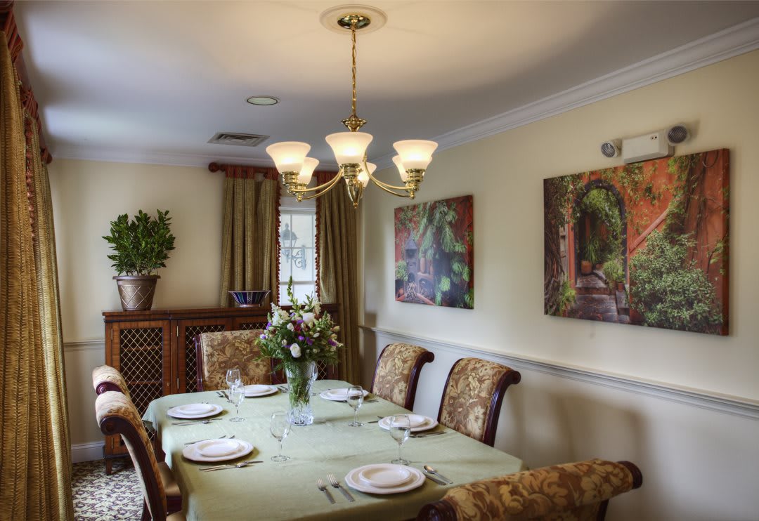 A well-decorated dining room with a set table, chandelier, and wall art.