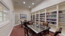 A small library room with bookshelves, a table, and chairs.