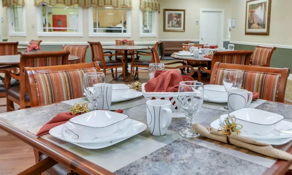 A neatly arranged dining area with tables set for a meal, featuring plates, glasses, and folded napkins.