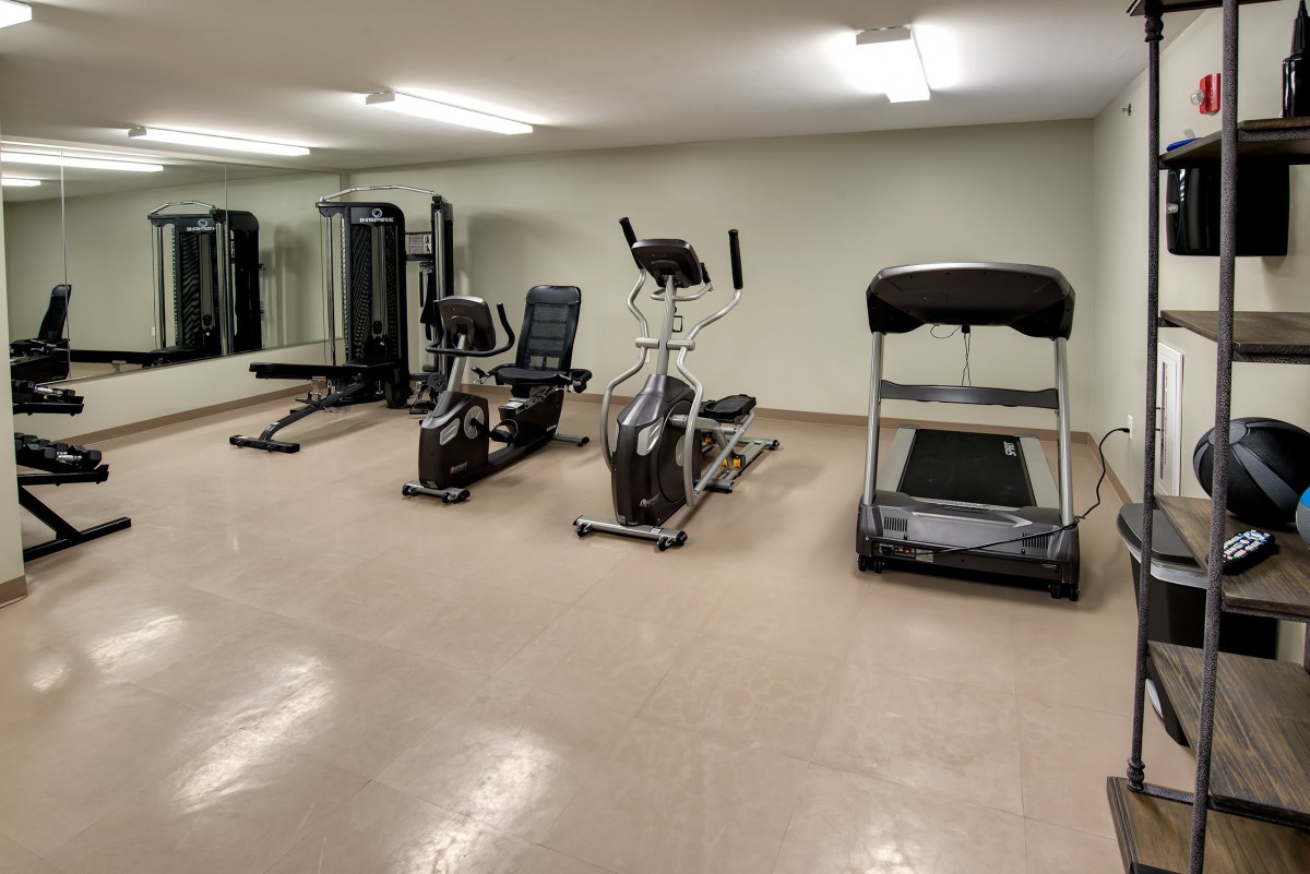 A small gym room equipped with various exercise machines, including a treadmill and an elliptical.